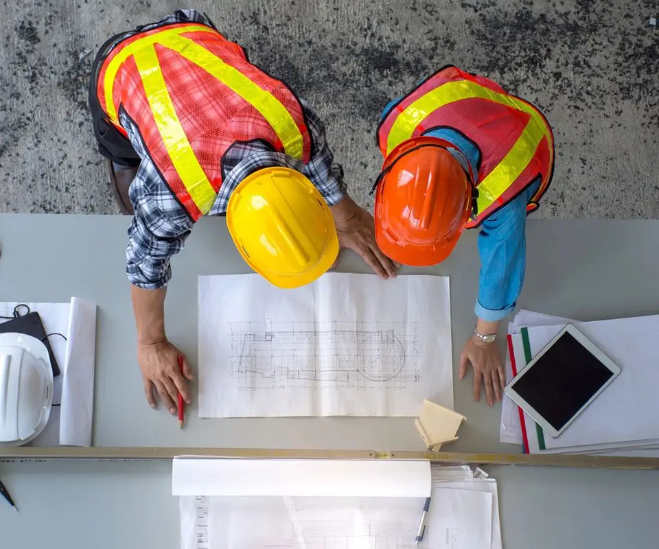 task2 (1) Two construction workers looking at a plan on top of the table.